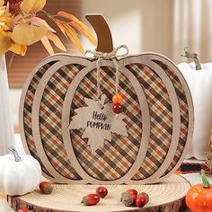 a wooden pumpkin with the words hello pumpkin on it sitting next to other fall decorations