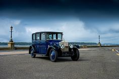 an old car is parked on the side of the road in front of dark clouds