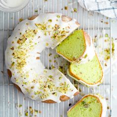 a green cake with white frosting and sprinkles on a cooling rack