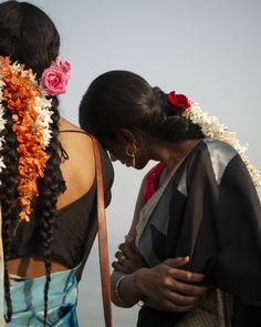 two women standing next to each other with flowers in their hair and one wearing a flower lei