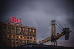 a large building with a lit up sign on it's roof next to a crane