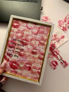 a person holding up a framed piece of paper with words on it and some pink flowers