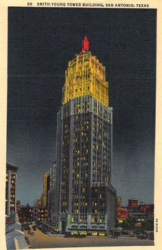 an old photo of a tall building lit up in yellow and white lights at night