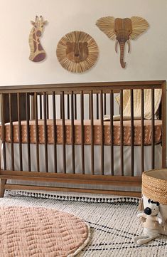 a baby crib in a nursery with giraffes hanging on the wall