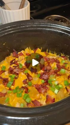 a crock pot filled with bacon and cheese on top of a table next to a stove