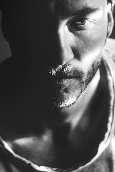 a black and white photo of a man's face with the sun shining on him