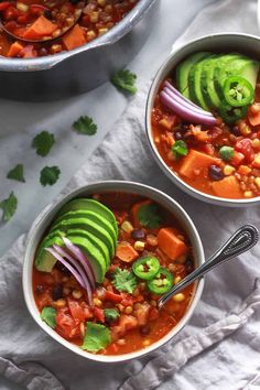 two bowls filled with chili, avocado and beans