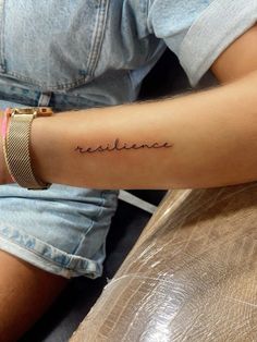 a woman's arm with the word resiline tattooed on her left arm