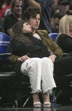 two people sitting next to each other at a basketball game