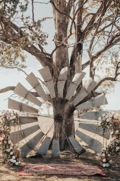 a large metal windmill sitting under a tree