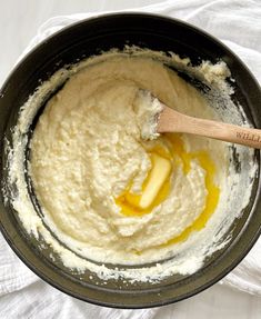 a wooden spoon mixing batter in a black bowl on top of a white table cloth