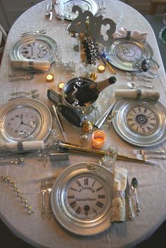 the table is set with silver plates and clock clocks, candles, and other items