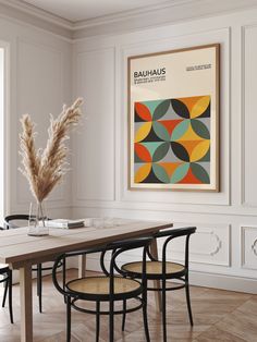 a dining room table with chairs and a large poster on the wall above it that says bauhauus