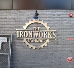 the ironwork's apartments sign on a brick wall in front of a chain link fence