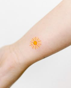 a person's arm with an orange and yellow sun tattoo on the left side of their arm