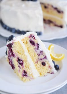 a slice of cake with blueberries and lemon is on a plate next to the rest of the cake