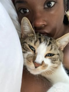 a woman holding a cat in her arms and looking at the camera with an intense look on her face