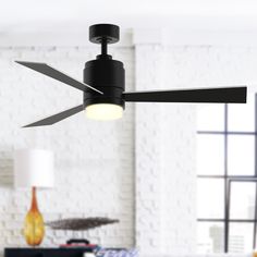 a black ceiling fan in a living room with white brick walls and floor to ceiling windows