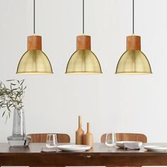 three pendant lights hanging over a dining room table