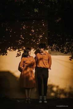 two people standing next to each other in front of a wall with shadows on it