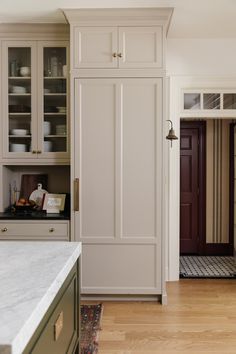 a kitchen with white cabinets and wood floors