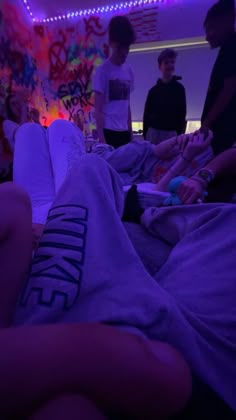 a group of people standing and sitting in a room with purple lights on the ceiling