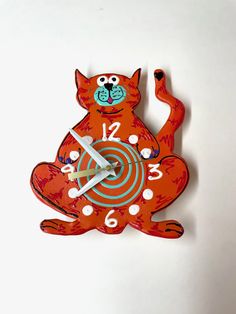 an orange cat clock with white dots on the face and numbers in the body, as well as hands