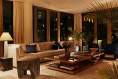 a living room filled with lots of furniture and large windows overlooking the city at night