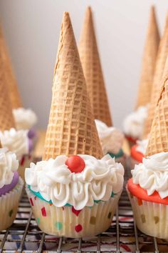 cupcakes with ice cream cones are sitting on a cooling rack