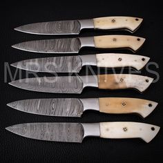 five knives are lined up next to each other on a black surface with holes in them