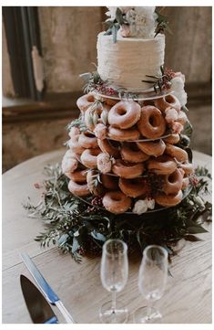 a wedding cake made out of doughnuts on top of a table with wine glasses