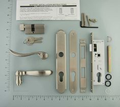 an assortment of door handles and hardware on a blue surface with a ruler next to it