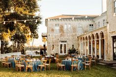 an outdoor dining area with tables and chairs in front of a large brick building on the lawn