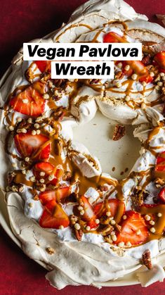 a cake covered in whipped cream and strawberries on top of a red tablecloth