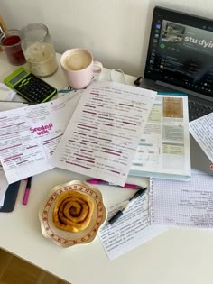 a laptop computer sitting on top of a desk covered in papers