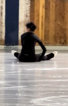 a woman sitting on the floor in front of a building with no one around her