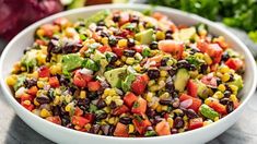 a white bowl filled with black beans, corn and avocado