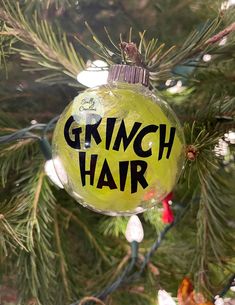 a glass ornament with the words grinch hair on it hanging from a pine tree