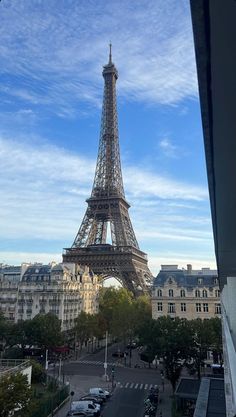 the eiffel tower in paris is seen from across the street, with cars parked below it