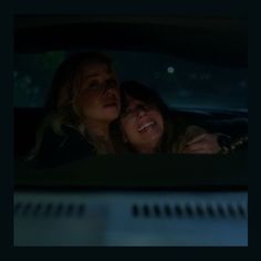 two women sitting in the back seat of a car, one is hugging the other