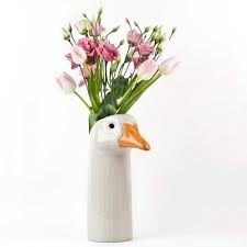 a duck vase with pink and white flowers in it