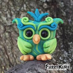 a green and blue owl sitting on top of a tree branch