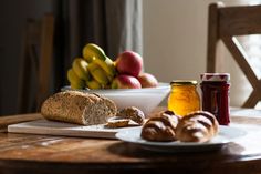 a table with bread, jam and fruit on it