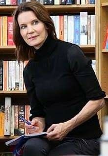 a woman sitting in front of a book shelf