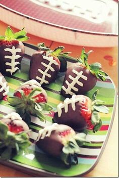 chocolate covered strawberries are arranged in the shape of footballs on a striped plate