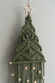 a crocheted christmas tree hanging on a wall with wooden beads and star decorations