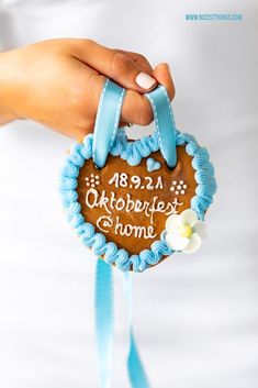 a person holding a decorated cookie with the words oktoberfest and home written on it