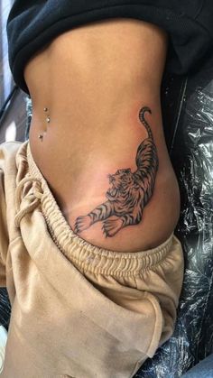 a woman's stomach with a tiger tattoo on her lower back and the side