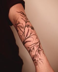 a woman's arm with flowers and leaves tattooed on the side of her arm