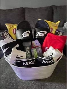 a white basket filled with nike slippers and other personal items on top of a couch